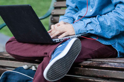 Person sitting on a bench, using a laptop computer