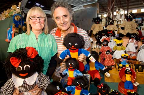 Woman and man standing at a display with around a dozen gollywog dolls.