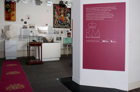 Entrance to Royal Melbourne exhibition. Large pink poster, display cabinets, white bust, alongside other ephemera