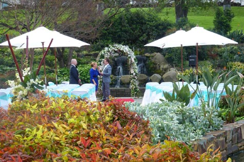 People standing in front of wedding chairs and umbrellas.