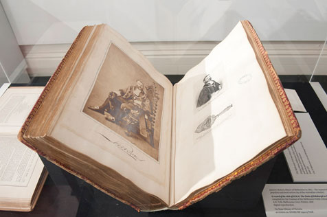 Large open book showing sepia phtograph of a king