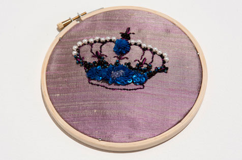 Embroidery hoop featuring a hand-sewn crown incorporating electric blue sequins, white pearls and a silk blue flower