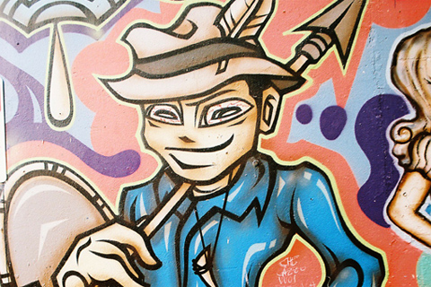 Bright, stylised painting of a man wearing a hat and carrying a spear.