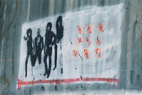 Street art of white square with stylised black image of a band.