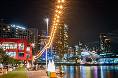 The Yarra River board walk at night, with the brightly lit ciity buildings in the background