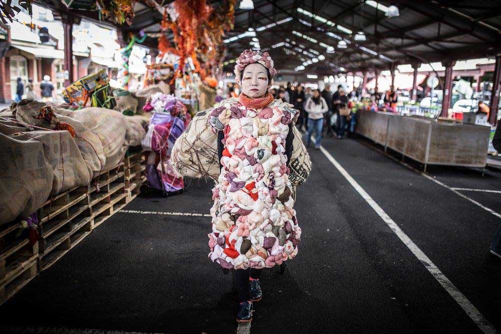 A woman wearing an artwork while standing in the middle of a Shed at the Queen Victoria Market