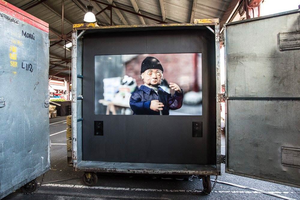 An open metal storage cart with a projected animation of a man dancing with his eyes closed.