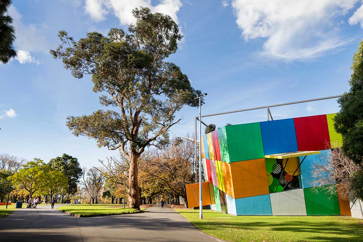 A section of the Melbourne Museum building resembling a tilted cube tiled in rainbow colours.
