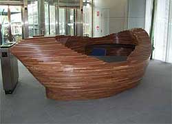 The concierge desk has a pod-like organic shape and is built from many thin layers of wood