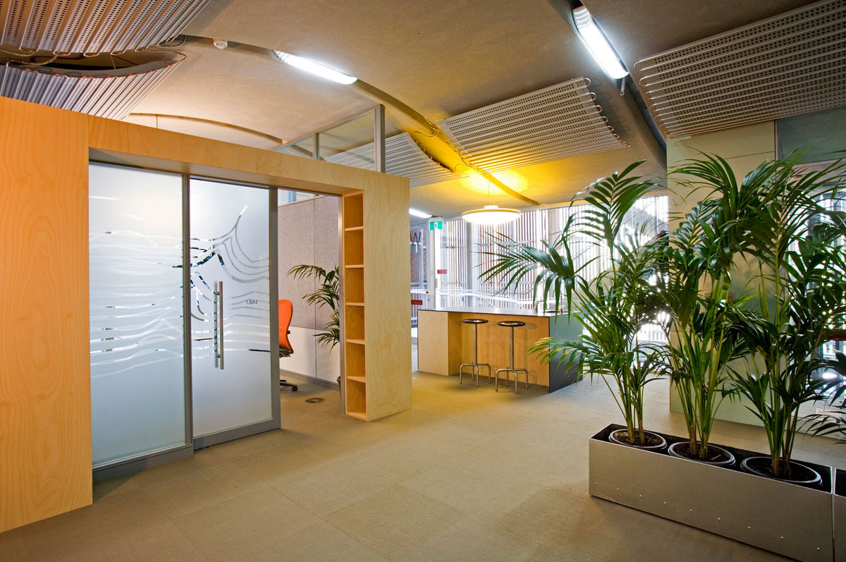 A meeting room with frosted glass doors and a row of tall plants just outside