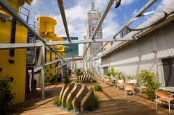 Rooftop with seating areas and plants under a metal pergola,