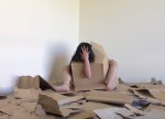 Person in the corner of a room surrounded by cardboard