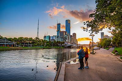 Two people standing next to the Yarra River, near the Melbourne CBD