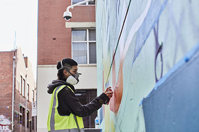 Woman wearing a face mask installing artwork on wall