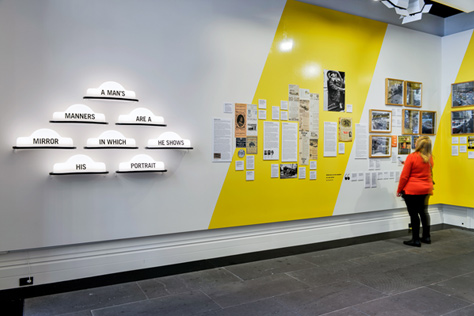 Woman looking at pictures on a white and yellow gallery wall