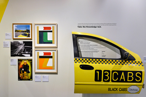 Close-up of the door of a yellow taxi cab and five small paintings/photographs