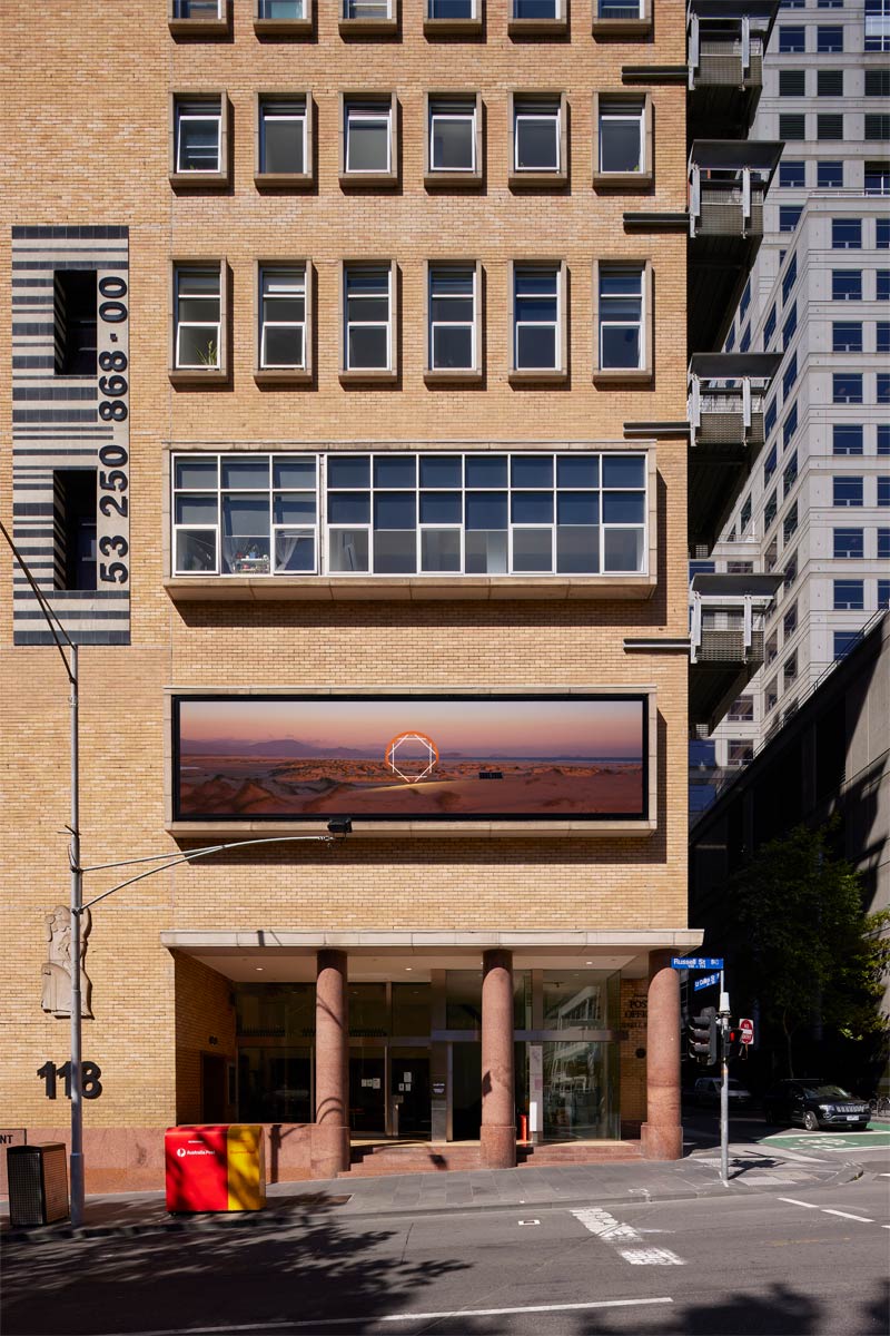 The artwork installed on the building, viewed from directly across the street and showing the four floors above the artwork.