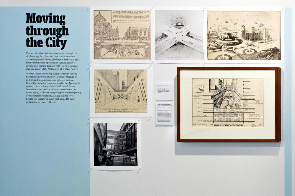 'Moving through the City' exhibit showing a photo of airbridges; line drawings of various streetscapes, multi-level and underground road systems and futuristic flying vehicles over Melbourne