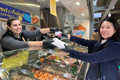A student shopping at a market seafood stall