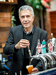 Nick Grigoriadis behind the bar at the Royal Melbourne Hotel, pouring a pot of beer from a tap.