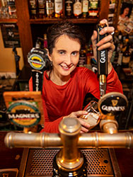 Siobhan Dooley filling a beer glass with Guiness from a tap at The Drunken Poet bar.