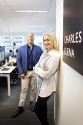 Sandy Tsindos and David Neilson standing in an office next to a sign on a wall that reads ‘Charles Elena’.