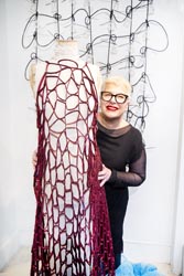 Vivian Dourali standing next to a mannequin displaying a bright, see-through crotched dress.