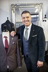 Smiling man next to suit display on mannequin