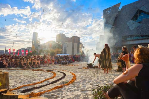 Melbourne Festival event at Federation Square with performers on sand-covered ground