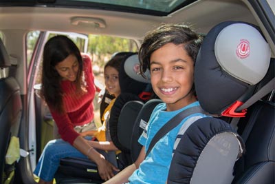 Children being strapped into safety seats in a car