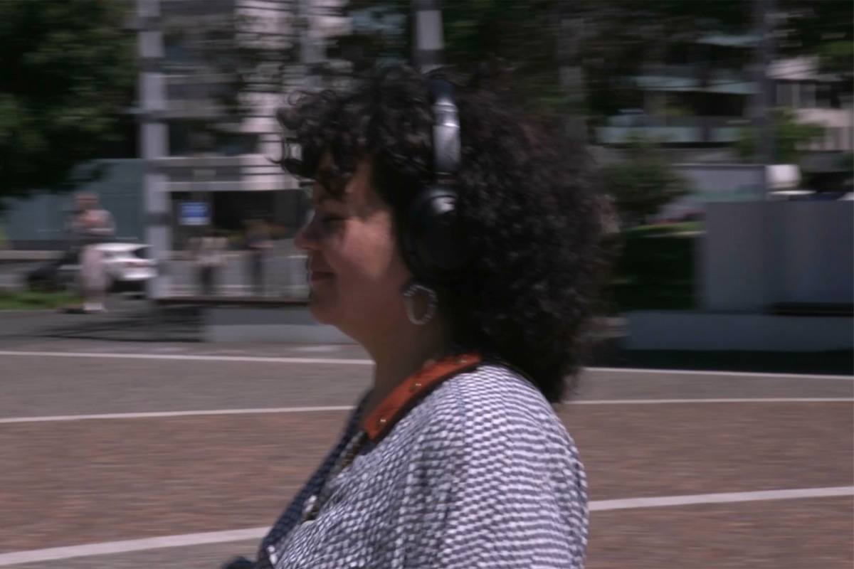 A photograph of a person walking while wearing over-ear headphones.