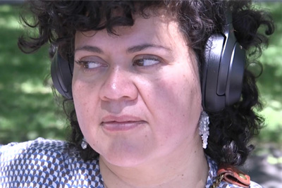 A photograph of a person wearing headphones looking to the side. 