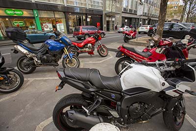 Motorcycles parked on street in a centre-of-road parking area.