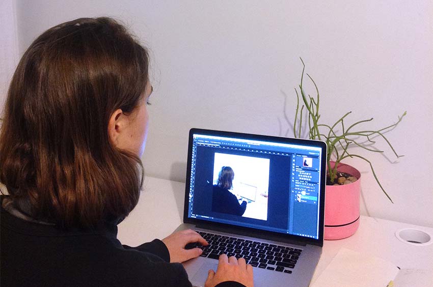 Women using a laptop; an image on the screen is echoing the same view of her using the laptiop