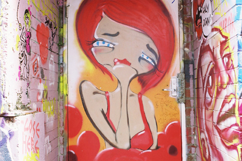 Stylised painting on a door of a woman with red hair in a red dress.