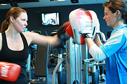 Female gym member with her personal trainer doing boxing 