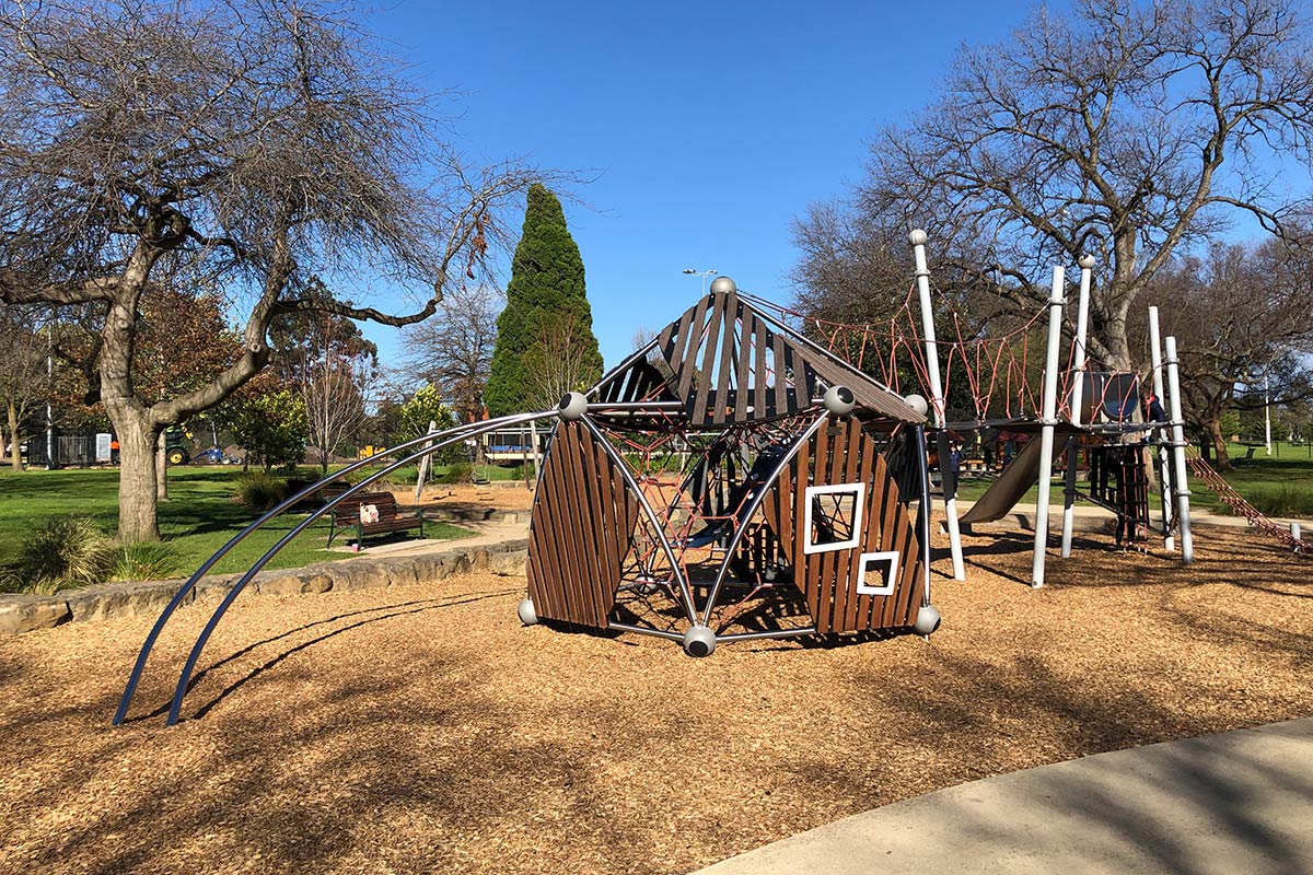 Children's playground featuring a climbing frame with slatted wooden panels.