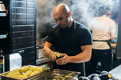 Chef Shane Delia preparing vegetables in a restaurant kitchen