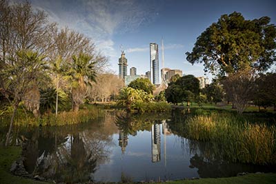 The Eureka Tower and Arts Centre reflected in an ornamental pond in Queen Victoria Gardens. 