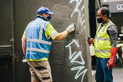 Cleaners removing graffiti from a wall.