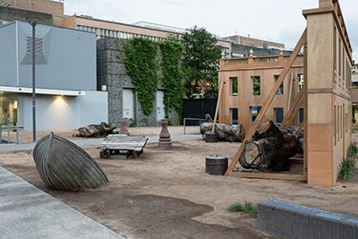 Installation of the artwork in the park, showing two of the facades of the building and other artefacts.