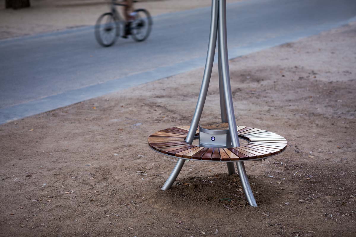 The solar tree's wooden bench. A cyclist rides past on the adjacent bike path