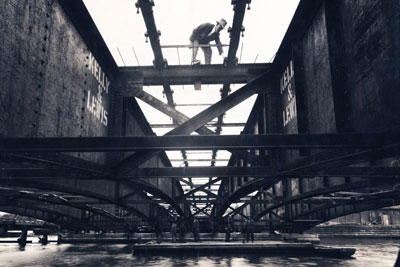 Black and white image of a man on a steel beam.