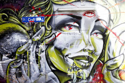 Street artwork of a woman with three eyes holding up her hands