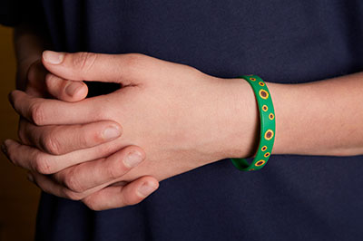 Hand and forearm with green bracelet showing sunflowers