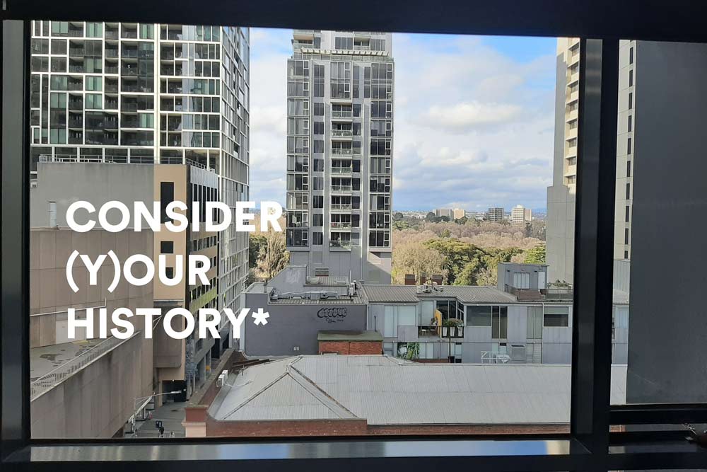 The words 'CONSIDER (Y)OUR HISTORY*' shown in large white text, against a background view through a window showing high-rise buildings and rooftops and sky, buildings and trees in the distance.