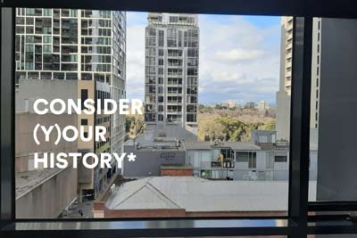 View through a window of high-rise buildings and rooftops, with the words 'CONSIDER (Y)OUR HISTORY*' shown in large white text .