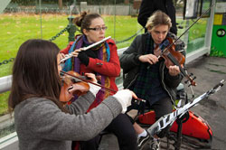 Two violinists and a flautist performing at a Melbourne tram stop