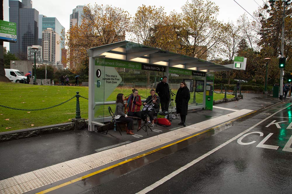 Two violinists, flautist and two other people at the Parliament Station tram stop (Stop 10)