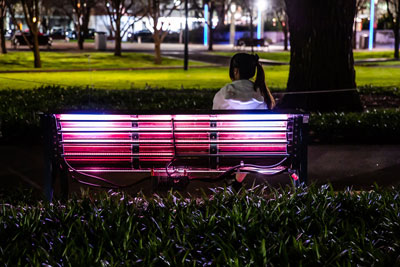 A park  bench lit by lights at night.